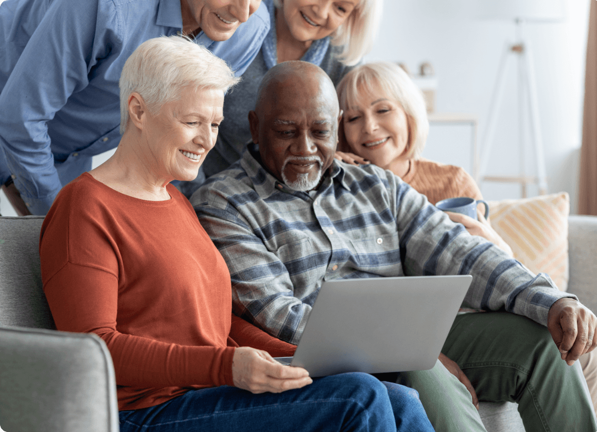 Seniors using a laptop together on a couch